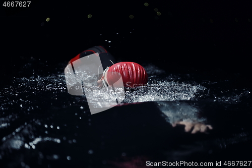 Image of triathlon athlete swimming in dark night wearing wetsuit