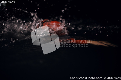 Image of triathlon athlete swimming in dark night wearing wetsuit