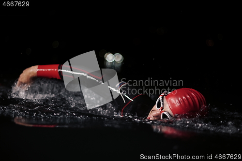 Image of triathlon athlete swimming in dark night wearing wetsuit