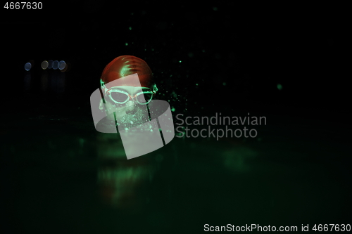 Image of authentic triathlete swimmer having a break during hard training on night neon gel light