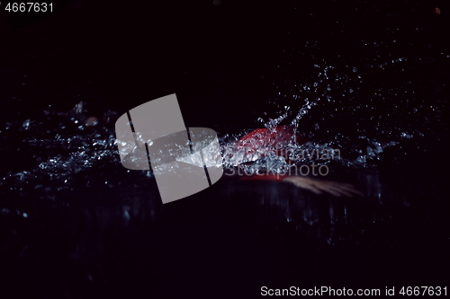 Image of triathlon athlete swimming in dark night wearing wetsuit