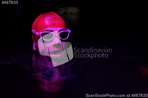 Image of authentic triathlete swimmer having a break during hard training on night neon gel light