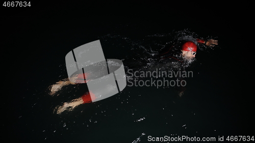 Image of triathlon athlete swimming in dark night wearing wetsuit