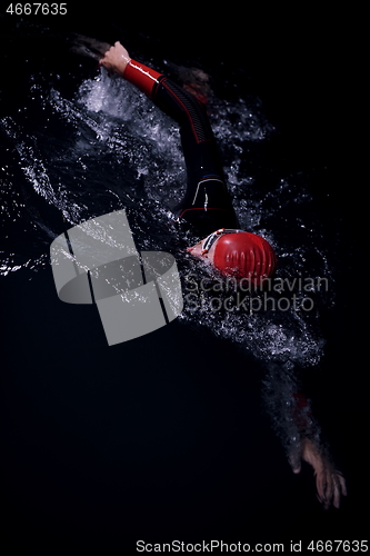 Image of triathlon athlete swimming in dark night wearing wetsuit