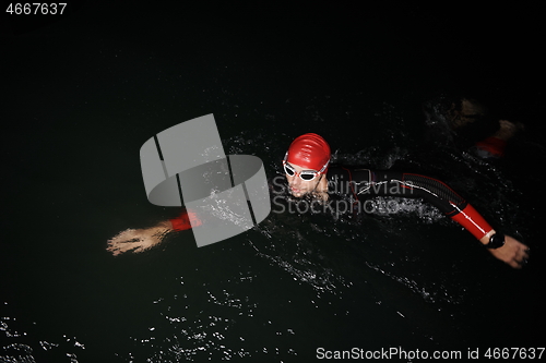 Image of triathlon athlete swimming in dark night wearing wetsuit