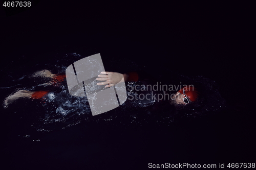 Image of triathlon athlete swimming in dark night wearing wetsuit