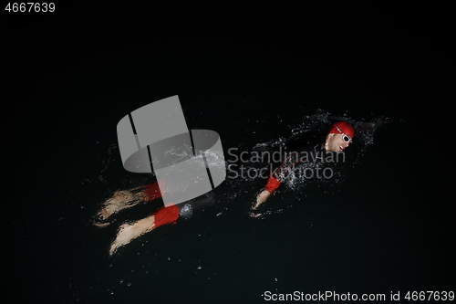 Image of triathlon athlete swimming in dark night wearing wetsuit