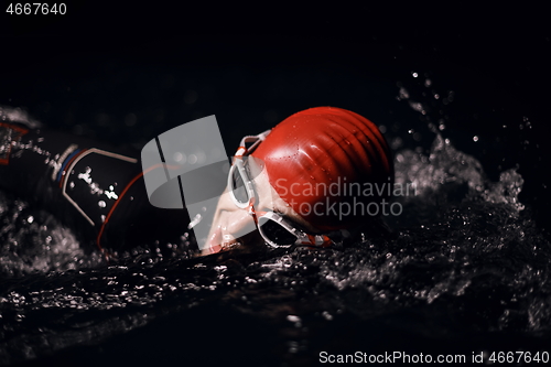 Image of triathlon athlete swimming in dark night wearing wetsuit