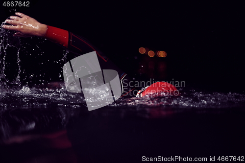 Image of triathlon athlete swimming in dark night wearing wetsuit