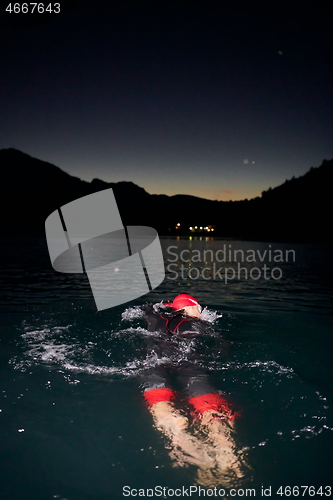 Image of triathlon athlete swimming in dark night wearing wetsuit