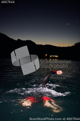 Image of triathlon athlete swimming in dark night wearing wetsuit