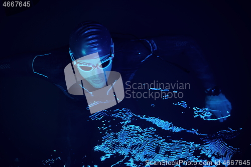 Image of authentic triathlete swimmer having a break during hard training on night neon gel light