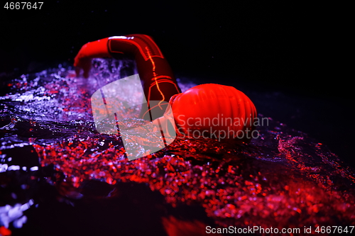 Image of real triathlon athlete swimming in dark night