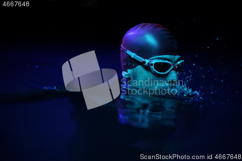 Image of authentic triathlete swimmer having a break during hard training on night neon gel light