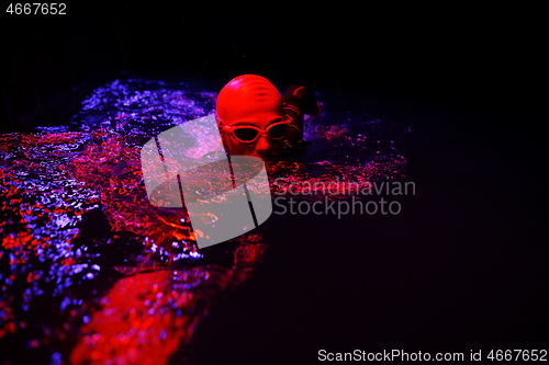 Image of real triathlon athlete swimming in dark night