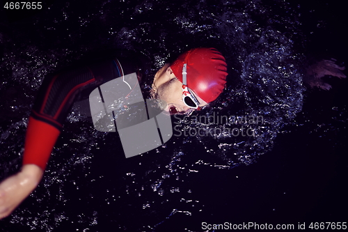 Image of real triathlon athlete swimming in dark night