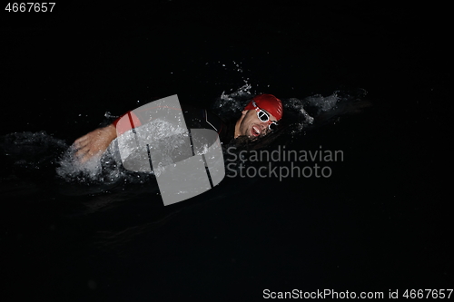 Image of triathlon athlete swimming in dark night wearing wetsuit