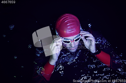 Image of authentic triathlete swimmer having a break during hard training on night