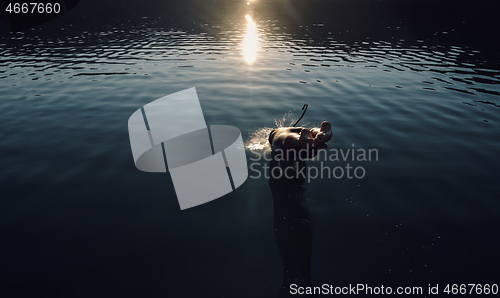 Image of triathlon athlete jumping in to water and starting with training