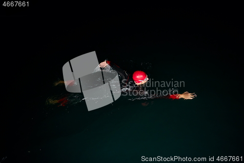 Image of triathlon athlete swimming in dark night wearing wetsuit