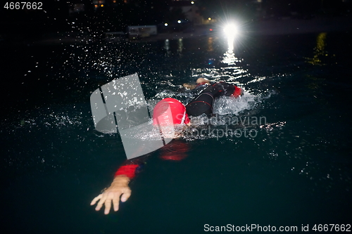 Image of triathlon athlete swimming in dark night wearing wetsuit