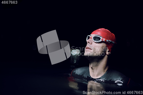 Image of authentic triathlete swimmer having a break during hard training on night