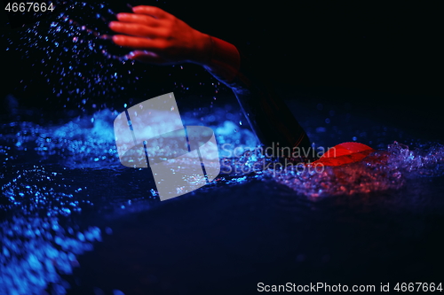 Image of real triathlon athlete swimming in dark night