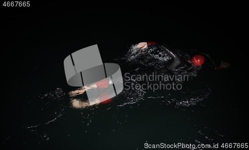 Image of triathlon athlete swimming in dark night wearing wetsuit