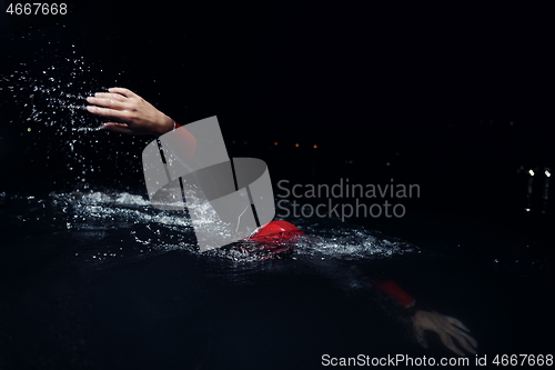 Image of triathlon athlete swimming in dark night wearing wetsuit