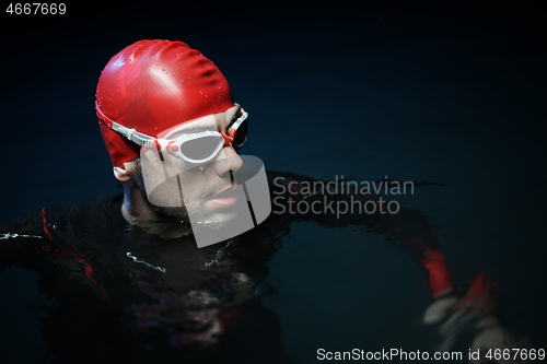 Image of authentic triathlete swimmer having a break during hard training on night