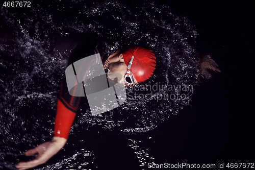 Image of triathlon athlete swimming in dark night wearing wetsuit