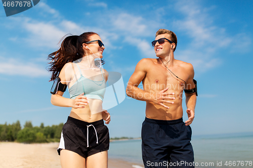 Image of couple with phones and arm bands running on beach