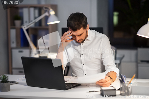 Image of businessman with papers working at night office