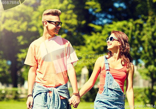 Image of happy teenage couple walking at summer park