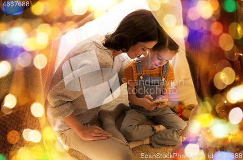 Image of happy family with smartphone in kids tent at home