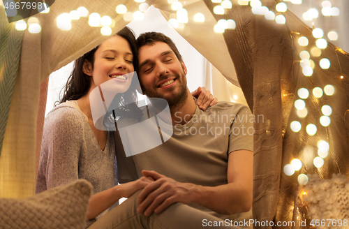 Image of happy couple in kids tent at home