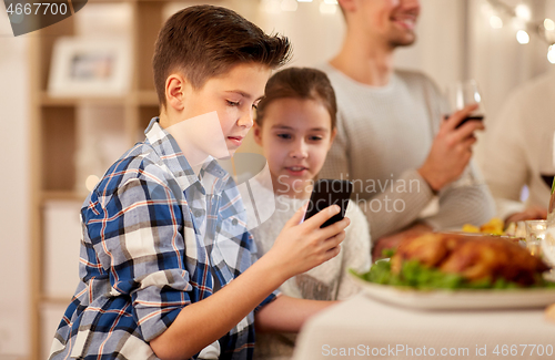 Image of boy with sister using smartphone at family dinner