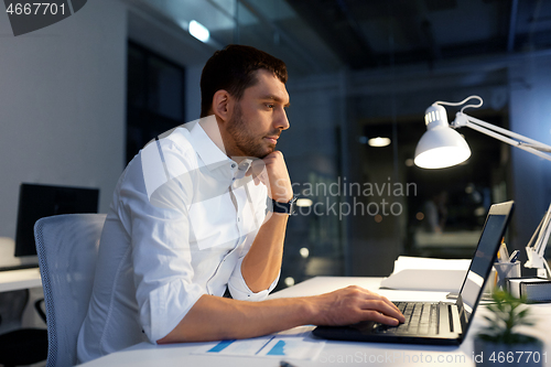 Image of businessman with laptop working at night office