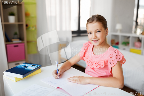 Image of student girl with book writing to notebook at home