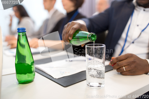 Image of businessman pouring water to glass at conference