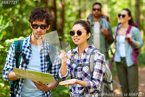 Image of friends with map and backpacks hiking in forest