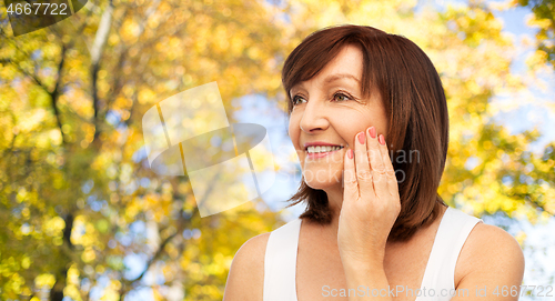Image of portrait of smiling senior woman touching her face