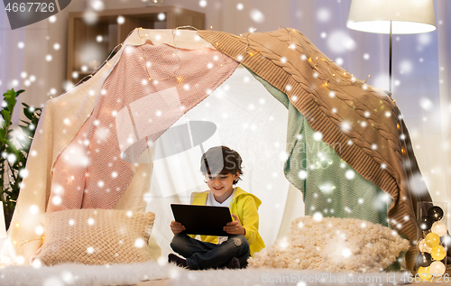 Image of little boy with tablet pc in kids tent at home