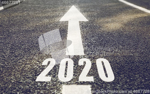 Image of white road marking in form of 2020 year and arrow