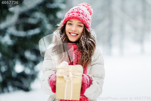 Image of happy young woman with christmas gift in winter