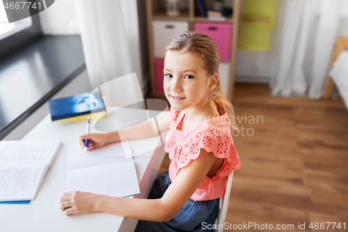 Image of student girl with book writing to notebook at home