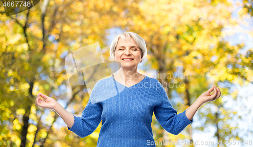 Image of smiling senior woman chilling in autumn park