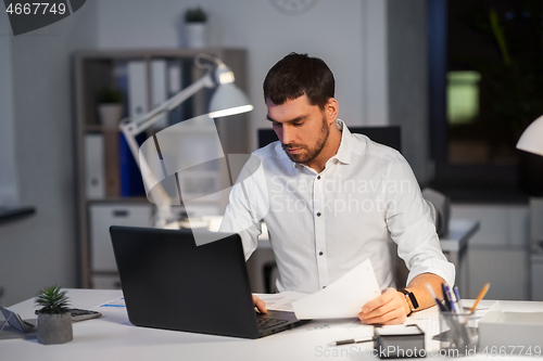 Image of businessman with laptop working at night office