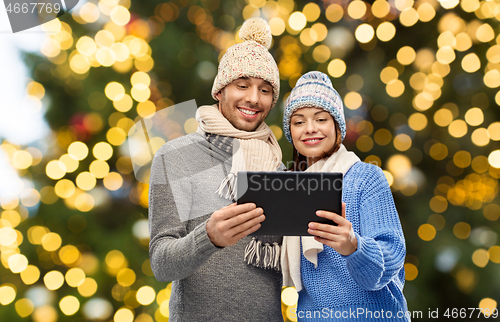 Image of couple with tablet computer over christmas lights