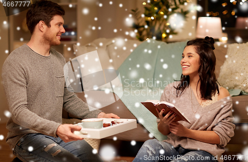 Image of happy couple with book and food at home